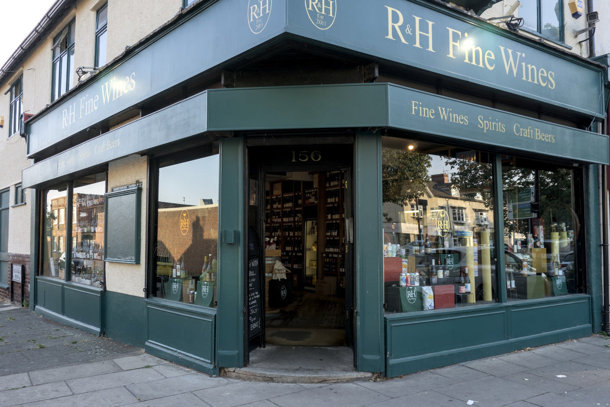R.H Fine Wines storefront on a city street, with dark green awnings and trim, large windows, and visible wine bottles inside.